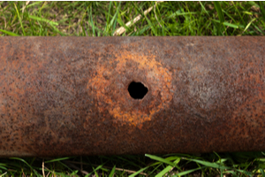 A hole rusted into an iron pipe.